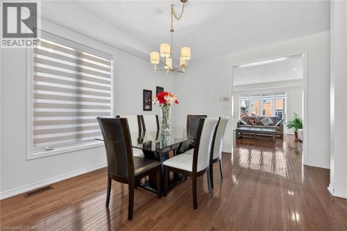 Dining space featuring a chandelier and dark wood-style floors - 97 Sirente Drive, Hamilton, ON 