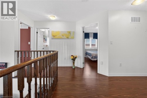 Hall with a textured ceiling, dark wood finished floors, and an upstairs landing - 97 Sirente Drive, Hamilton, ON 
