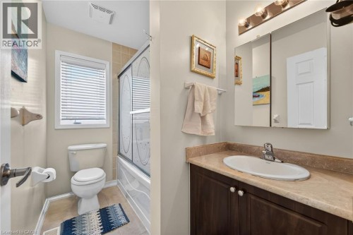 Full bathroom with vanity, enclosed tub / shower combo, and light tile patterned flooring - 97 Sirente Drive, Hamilton, ON 