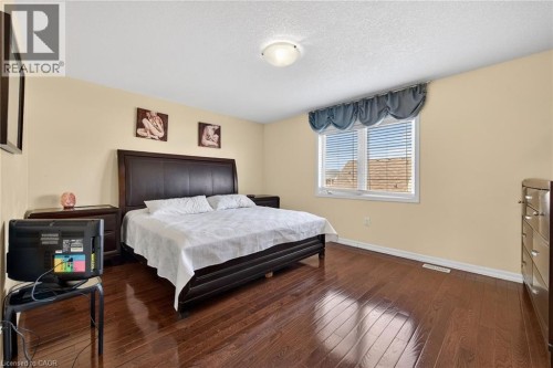 Bedroom featuring dark wood finished floors and a textured ceiling - 97 Sirente Drive, Hamilton, ON 