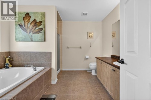 Full bath with vanity, a shower stall, a bath, and dark tile patterned flooring - 97 Sirente Drive, Hamilton, ON 