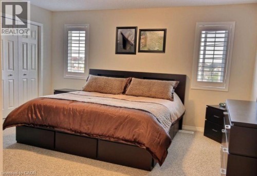 Neutral-toned walls, two windows with plantation shutters, carpeted flooring, and bi-fold closet doors - 507 Beaumont Crescent, Kitchener, ON 