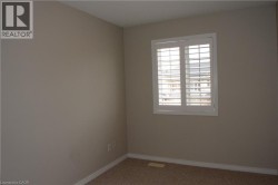 Window with white plantation shutters, neutral tone wall paint, and carpeting - 