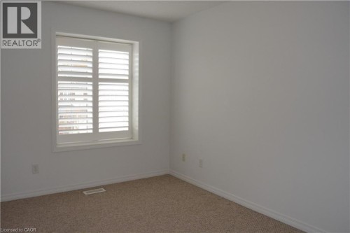 Neutral wall paint, carpeted flooring, and a window with plantation shutters - 507 Beaumont Crescent, Kitchener, ON 