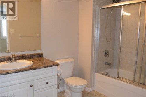 Bathroom featuring a vanity with an integrated sink, a tiled shower-tub combination with sliding glass doors, and a neutral color palette - 507 Beaumont Crescent, Kitchener, ON 