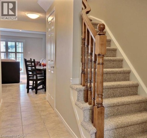 Wood-finish staircase railing with carpeted stairs, tiled flooring, and white paneled doors - 507 Beaumont Crescent, Kitchener, ON 