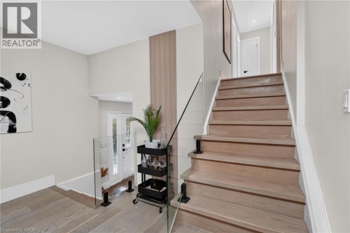 Light wood-finish staircase with clear glass railing - 9 Leslie Drive, Hamilton, ON 