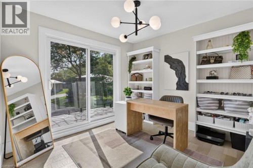 Room featuring wood-finish flooring, a modern chandelier with spherical lights, and light gray wall paint - 9 Leslie Drive, Hamilton, ON 