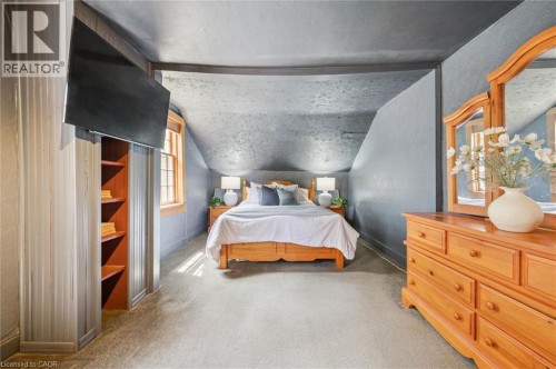 Sloped ceiling room featuring carpet flooring, natural wood-finish window trim, and a built-in shelving unit - 630 Robert Ferrie Drive, Kitchener, ON 
