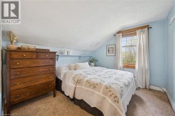 Sloped ceiling room featuring carpet flooring, built-in shelving, and a double-hung window with wood trim - 