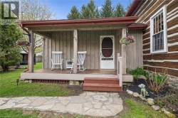 Covered front porch with wood plank siding, a decorative screen door, and a stone walkway - 
