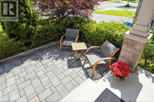 Elegant patio featuring permeable paver hardscaping, mature hedging for privacy, and comfortable seating arrangements - 173 Raymond Road, Ancaster, ON 
