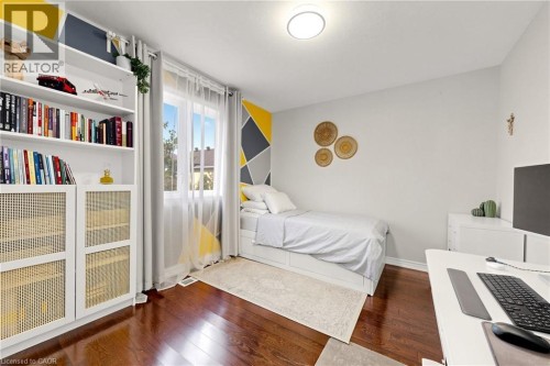 Hardwood flooring, built-in shelving with cane-front cabinetry, geometric accent wall, and a bright window with sheer and solid drapery - 173 Raymond Road, Ancaster, ON 