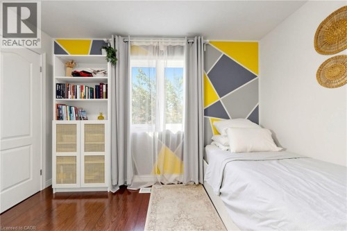 Wood-finish flooring with a built-in shelving unit featuring woven cabinet doors - 173 Raymond Road, Ancaster, ON 
