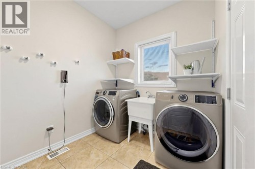 Tile flooring, white window trim, wall-mounted shelving, and a utility sink - 173 Raymond Road, Ancaster, ON 