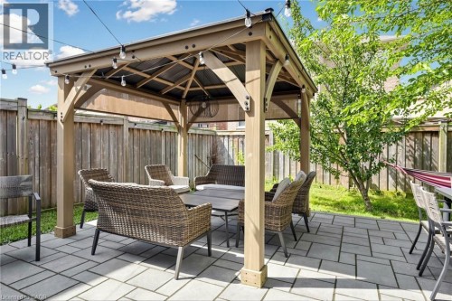 Covered patio with timber beam construction and retractable shade system, featuring paver flooring and integrated landscape lighting - 173 Raymond Road, Ancaster, ON 