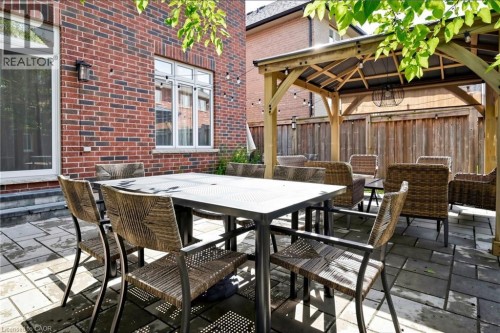 Paver patio featuring a wooden gazebo with a pitched roof, brick exterior, and privacy fencing - 173 Raymond Road, Ancaster, ON 