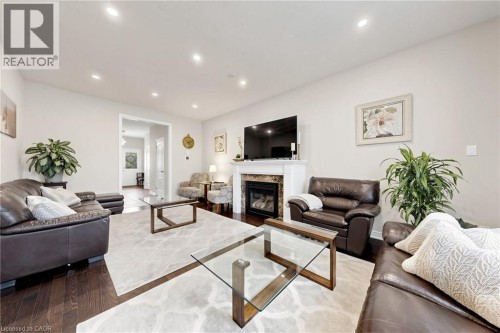 Hardwood flooring, recessed ceiling lighting, a fireplace with a stone surround, and a white mantel - 173 Raymond Road, Ancaster, ON 
