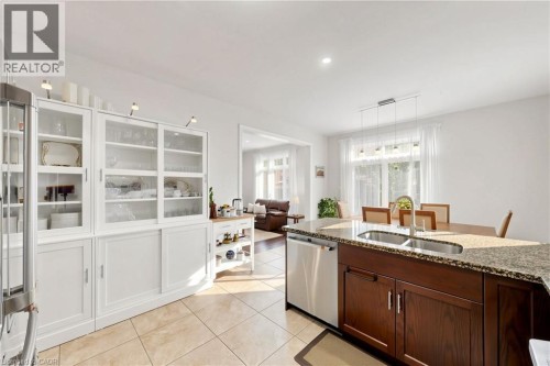 Kitchen featuring a central island with dual sinks, built-in dishwasher, and stone countertop - 173 Raymond Road, Ancaster, ON 