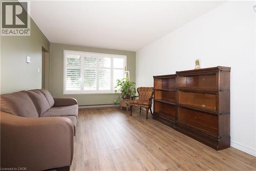 Wood-finish flooring with white baseboards, a window featuring white plantation shutters, and a wall with a light olive paint finish - 219 Foxhunt Road, Waterloo, ON 