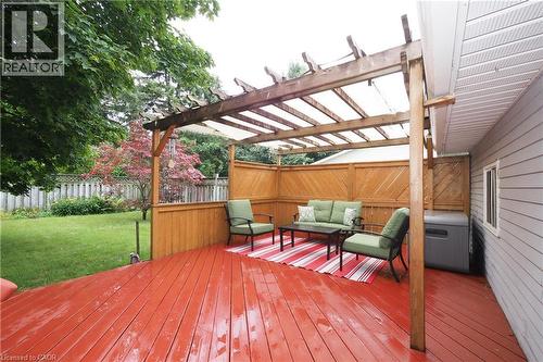 Expansive wood deck with a red finish, featuring a pergola with a translucent cover and privacy fencing - 219 Foxhunt Road, Waterloo, ON 