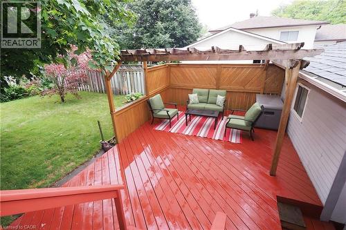 Expansive red-stained deck with a wooden pergola, privacy fencing, and manicured lawn - 219 Foxhunt Road, Waterloo, ON 