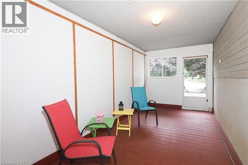 Enclosed porch featuring a red wood-finish floor, white paneled walls with wood trim, and a built-in ceiling light fixture - 219 Foxhunt Road, Waterloo, ON 