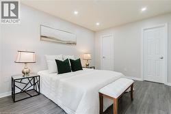 Recessed lighting, light gray walls, wood-finish flooring, and white paneled doors - 