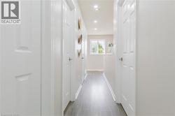 Hallway with light wood-finish flooring, recessed ceiling lighting, and white paneled doors - 