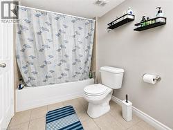 Full-sized bathtub with tiled surround, neutral wall color, and tile flooring - 