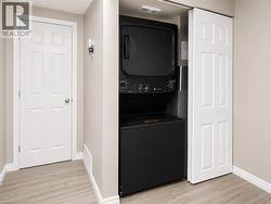 Stackable laundry appliances with concealed utility connections, paneled interior doors, and light wood-finish flooring - 