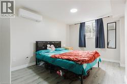 Wall-mounted HVAC unit, recessed ceiling lighting, light wood-finish flooring, and a single window - 