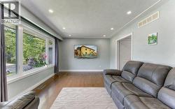 Hardwood-style flooring throughout, large picture window, recessed ceiling lighting, and a white interior door - 