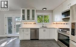 White shaker-style cabinetry with glass-front uppers, stainless steel appliances, and light-toned countertops - 