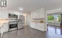 White cabinetry, stainless steel appliances, tile flooring, engineered stone countertops, and a wood-finish countertop - 