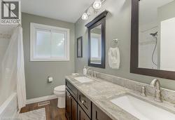 Dual vanity with undermount sinks, granite countertop, and dark wood-finish cabinetry - 