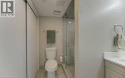 Sliding door closet, toilet, glass-enclosed shower, integrated sink vanity with white countertop - 
