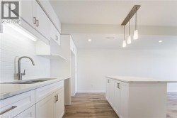 White shaker-style cabinetry with brushed nickel hardware, light-toned countertops, a stainless steel sink with a gooseneck faucet, white subway tile backsplash, and wood-finish flooring - 