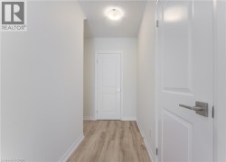 Hallway featuring wood-finish flooring, white paneled doors, and a flush mount ceiling light - 