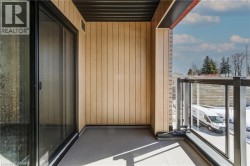 Sliding glass door access to an outdoor balcony featuring a glass and metal railing, vertical paneling, and an overhead soffit - 