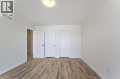 Wood-finish flooring with white baseboards, light neutral wall paint, and white paneled doors - 25 Urbane Boulevard, Kitchener, ON 
