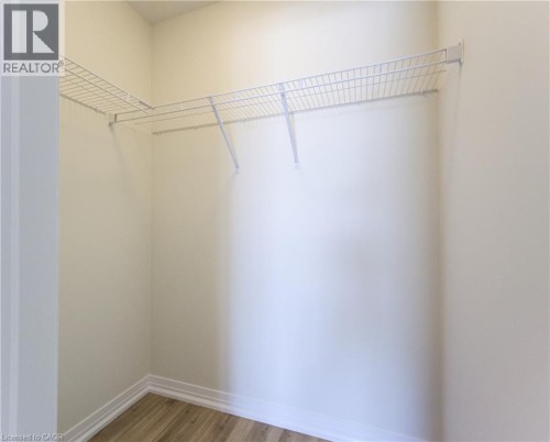 Walk-in closet featuring wire shelving, white walls, and wood-finish flooring - 25 Urbane Boulevard, Kitchener, ON 