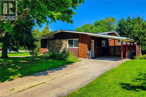 Brick and stone facade with a covered carport, mature trees, and a wooden privacy fence - 1 Vera Court, Hamilton, ON 