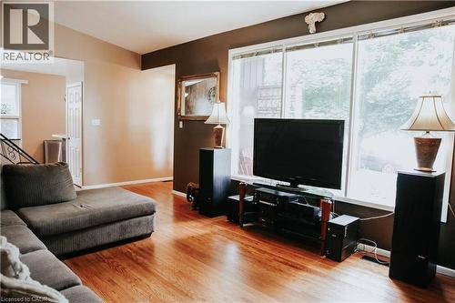 Hardwood-finish flooring, large window with white trim, framed mirror, and warm-toned wall finishes - 1 Vera Court, Hamilton, ON 