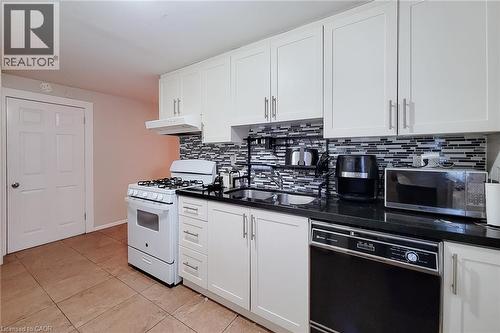 Kitchen featuring white cabinetry, black countertops, a mosaic tile backsplash, and tile flooring - 1 Vera Court, Hamilton, ON 