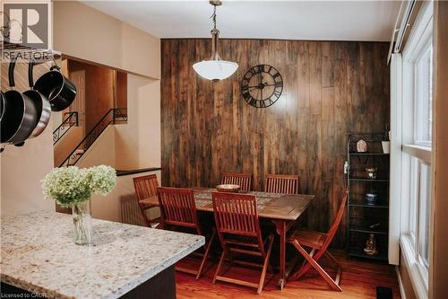 Wood-paneled accent wall, wood-finish flooring, built-in shelving, staircase with wrought iron railing, and a window with white trim - 1 Vera Court, Hamilton, ON 