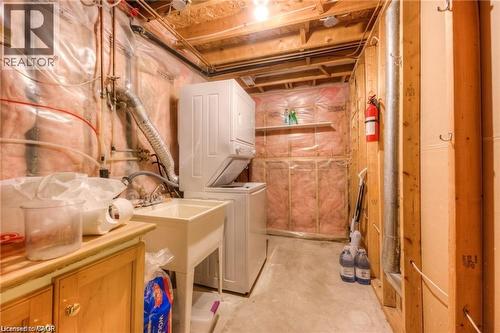 Laundry area featuring a utility sink, a stacked washer and dryer, and exposed wood framing - 8 Melran Drive Unit# 2, Cambridge, ON 