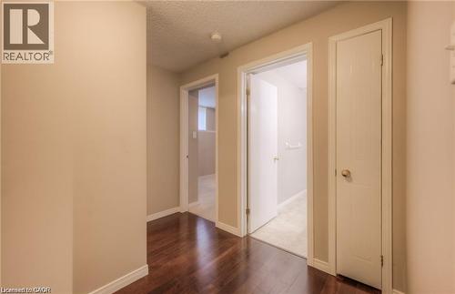 Hallway featuring wood-finish flooring, two white doors, and light neutral wall paint - 8 Melran Drive Unit# 2, Cambridge, ON 