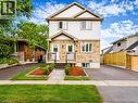 Split-level exterior with stone and siding facade, covered front porch, dual paved driveways, and landscaped front yard with mature trees - 67 Kinzie Avenue, Kitchener, ON 