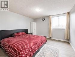 Bright bedroom with light gray walls, wood-finish flooring, a white wardrobe, and a large window with drapes - 